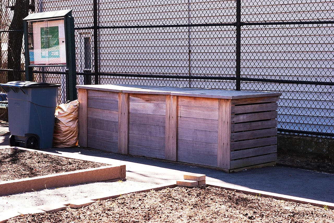 Des bacs à compost en bois à trois compartiments dans un jardin.